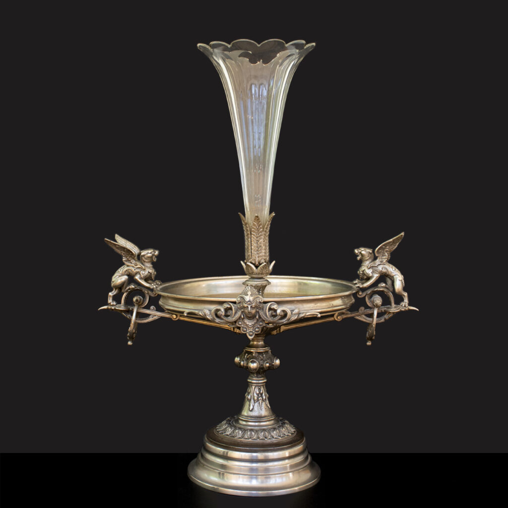 Épergne español del siglo XIX-XX con base metálica, figuras de leones alados y un cuenco decorativo central