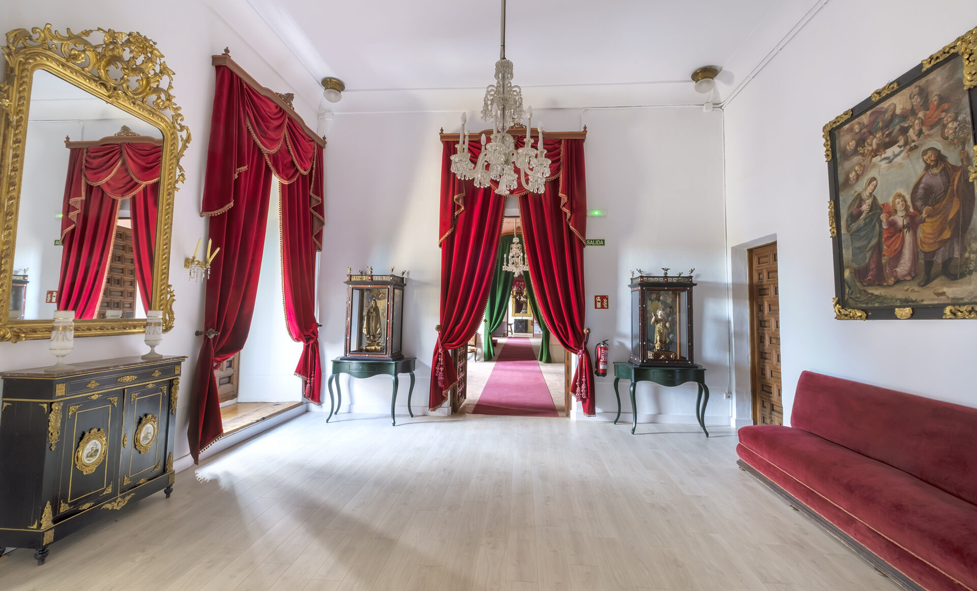 Antesala 1 del Palacio Episcopal de Segovia con cortinas rojas, muebles antiguos y decoración clásica