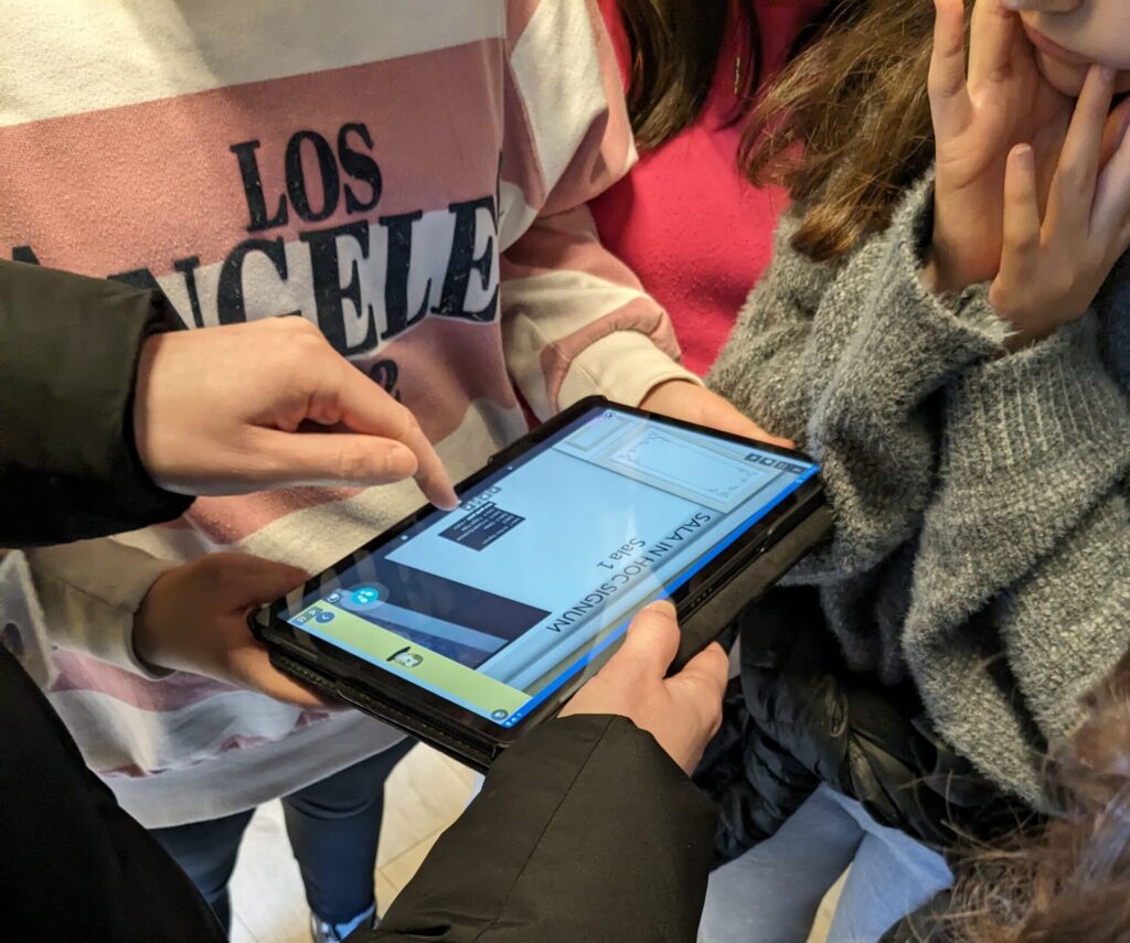 Jóvenes participando en un taller educativo interactivo en el Palacio Episcopal de Segovia, utilizando una tablet para resolver actividades.