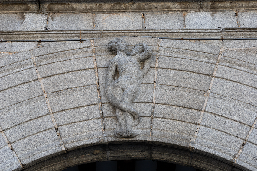 Primer plano del arco del Palacio Episcopal de Segovia con esculturas decorativas y un escudo en la parte superior.