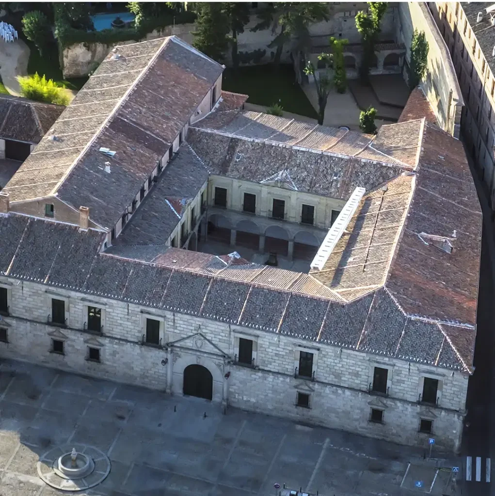 Vista aérea del Palacio Episcopal de Segovia, destacando su estructura rectangular con patio central y tejados inclinados.