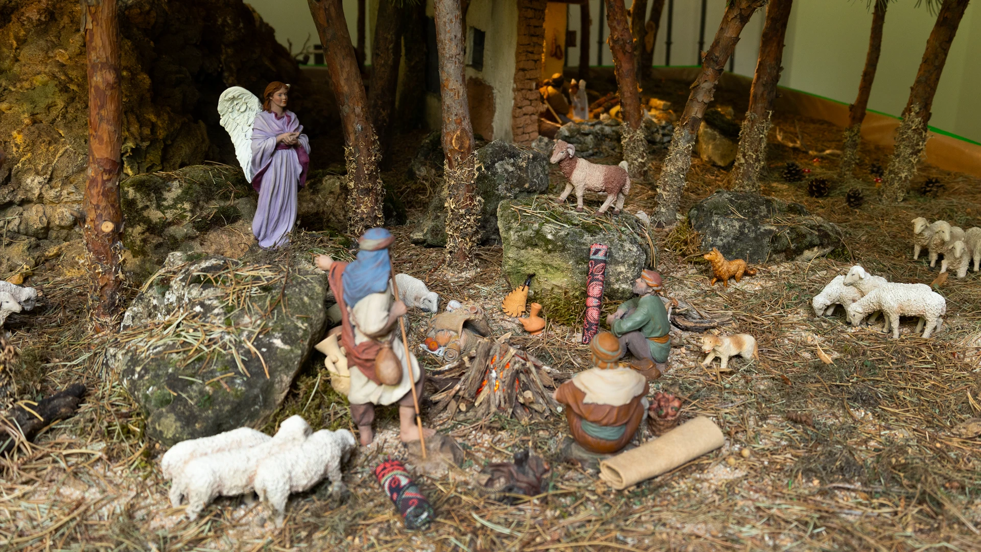 Escena del belén monumental en el Palacio Episcopal de Segovia con pastores junto a una fogata, rodeados de ovejas, un ángel y elementos de la vida rural