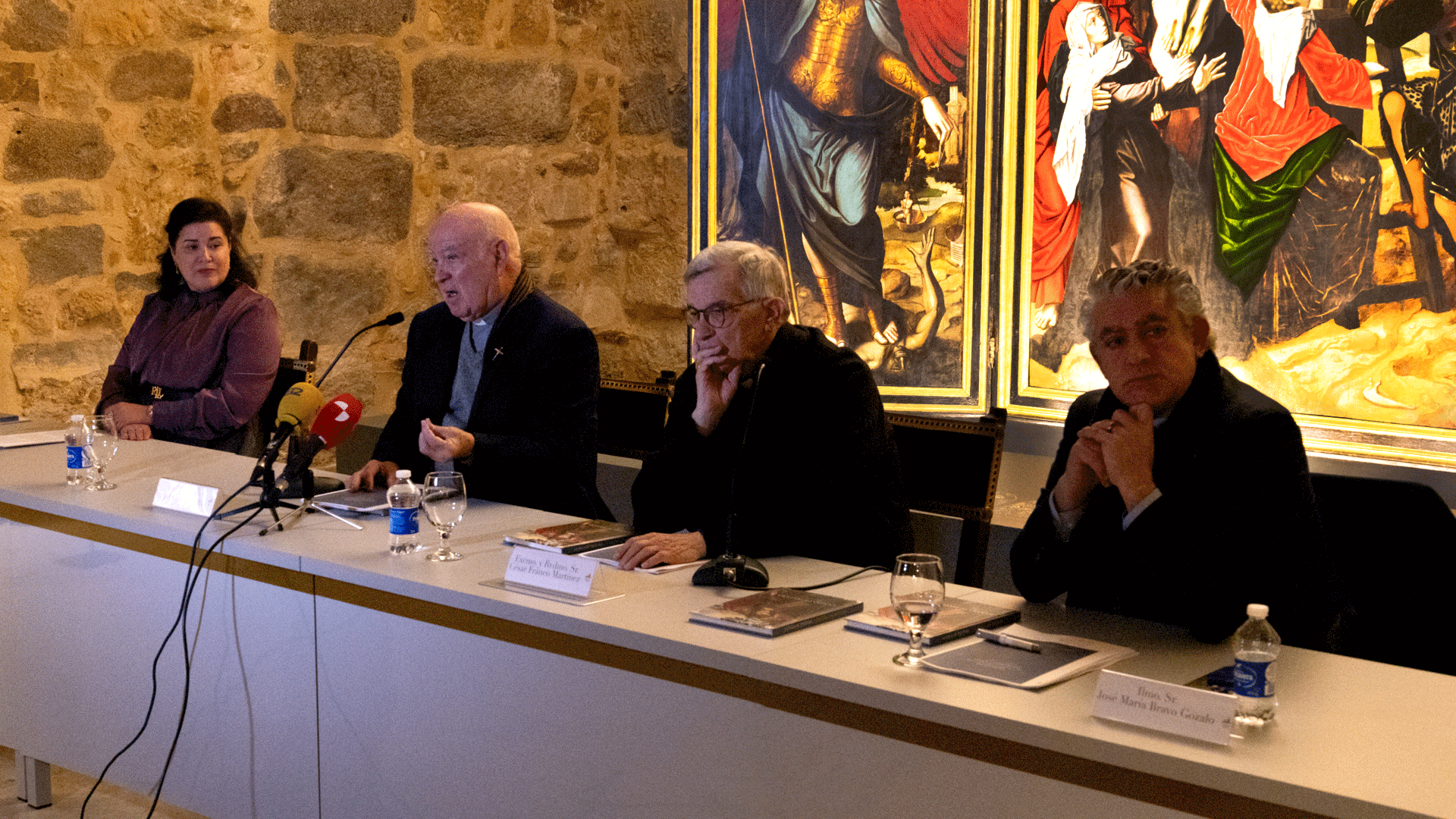 Acto de presentación del catálogo de la Sala de Pintura Bajo Claustro en la Catedral de Segovia con César Franco Martínez, José María Bravo Gozalo, Ángel García Rivilla y Gloria Martínez Leiva en una mesa de intervenciones, acompañados por obras de arte sacro de fondo.